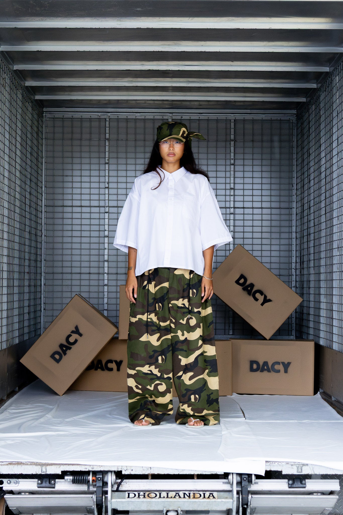 Model wearing camo tie hat with extended straps and baggy camo pants