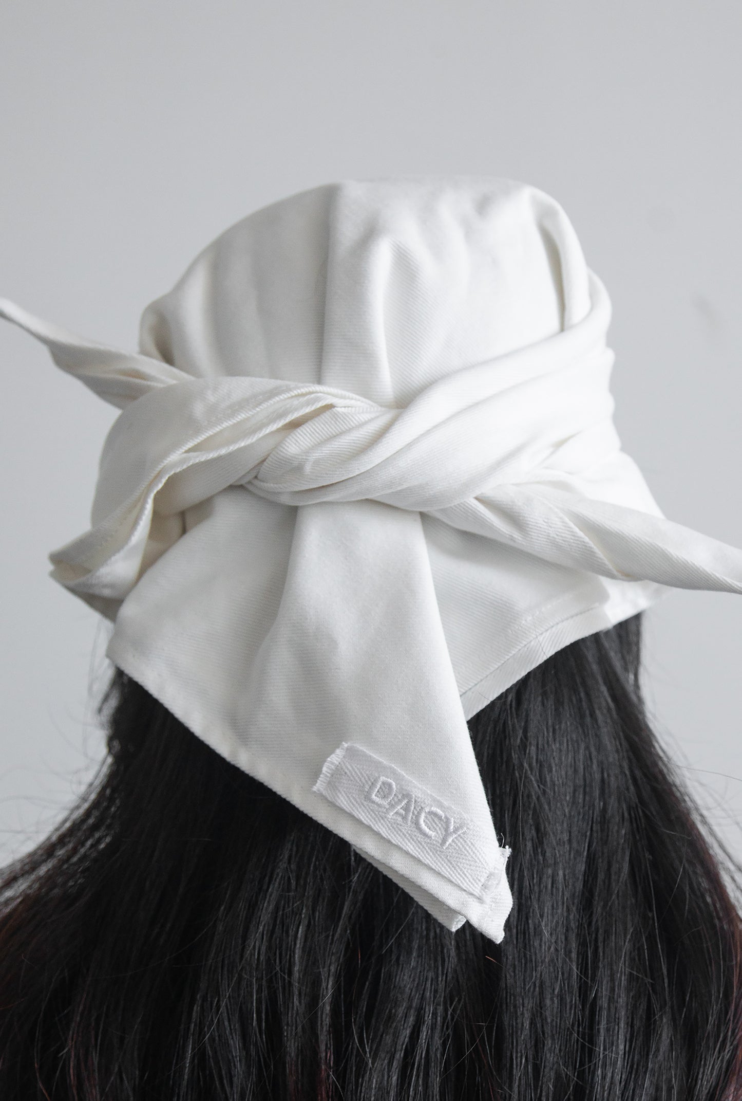 Back view of the DACY Studio Tie Hat in off-white cotton drill featuring an adjustable tie-back design and embroidered DACY logo.