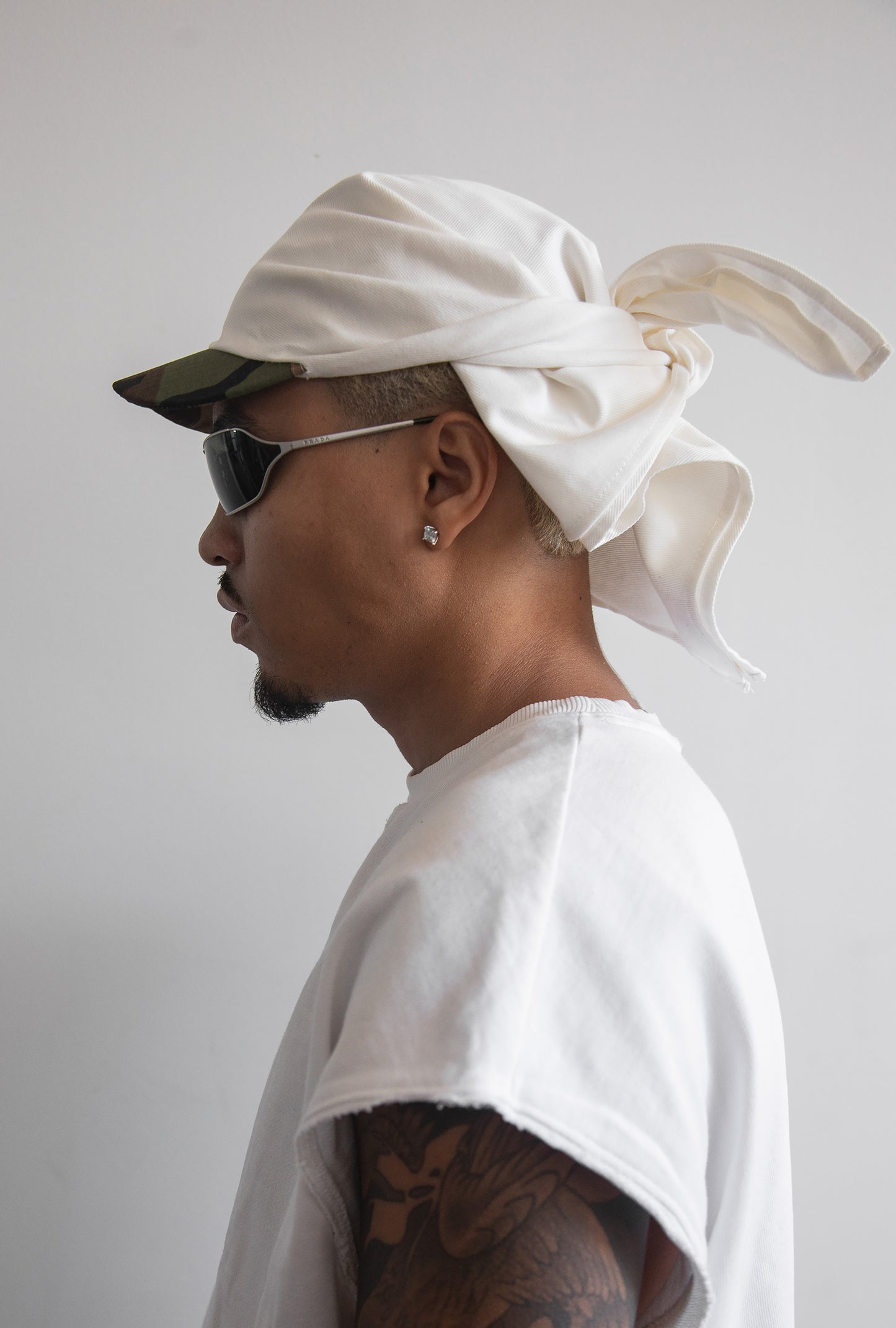 DACY Studio Tie Hat in off-white cotton drill with a short camo brim, adjustable tie-back and unisex silhouette.